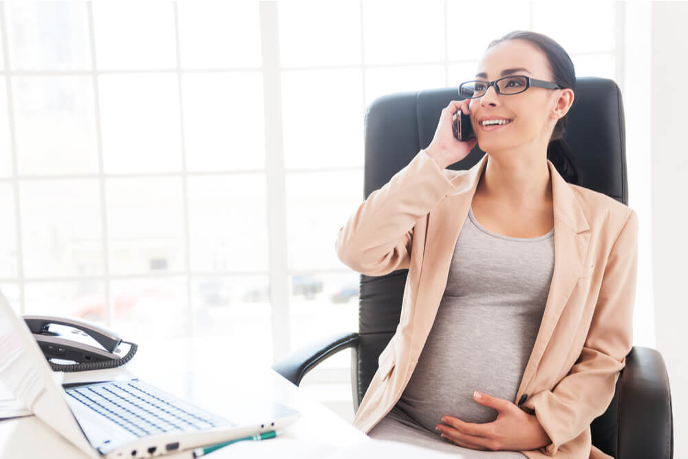職場で、笑いながら電話をしている妊婦
