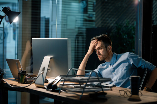 残業で頭を抱える男性