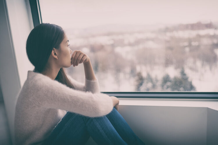 窓の外を見ながら憂鬱そうな表情をしている女性