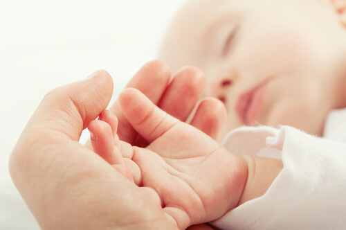 赤ちゃんの手を包む母親の手
