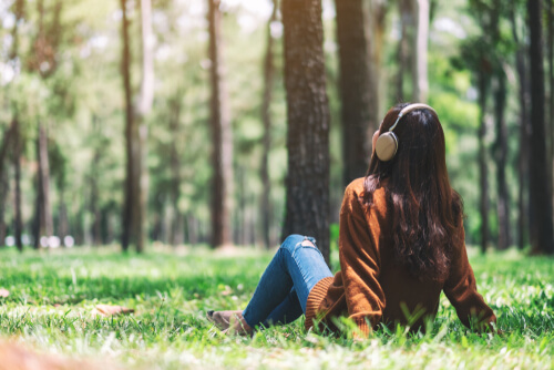 森林のなかで音楽を聴いてリラックスする女性