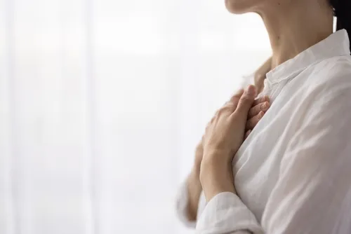 胸に手を当てる白いシャツを着た女性