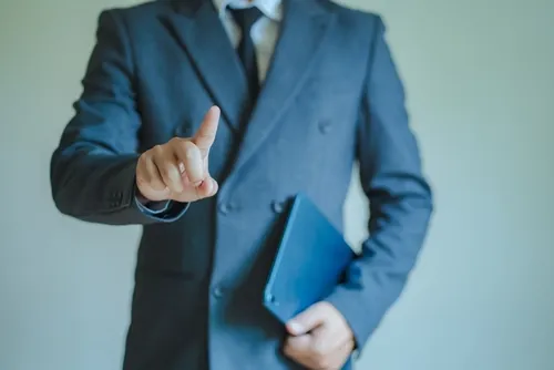 人差し指を立てているスーツの男性