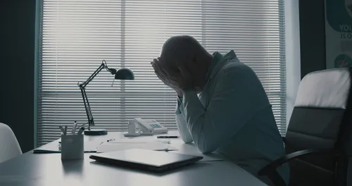 薄暗い部屋で頭をかかえる人