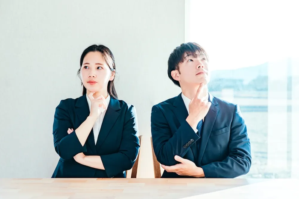 斜め上を見て考えごとをする男女