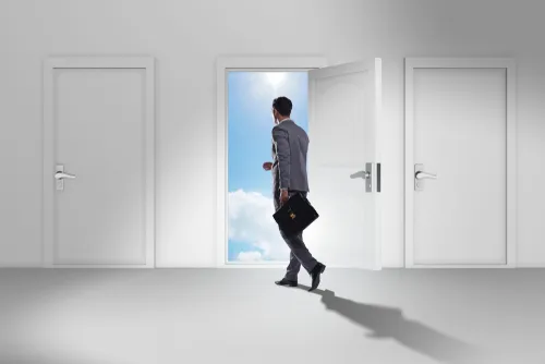 複数の扉から青空が見える扉を開けて進むビジネスマン