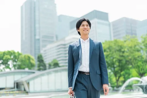 笑顔でビル街を歩く男性