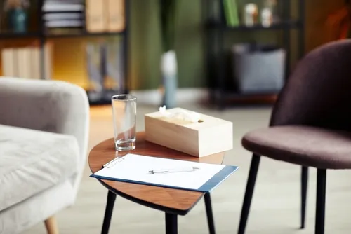 2脚の椅子とコップやティッシュ、バインダーが乗ったサイドテーブル