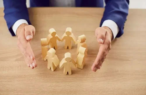 木製の人形が輪を作りそれを包み込もうとする手元