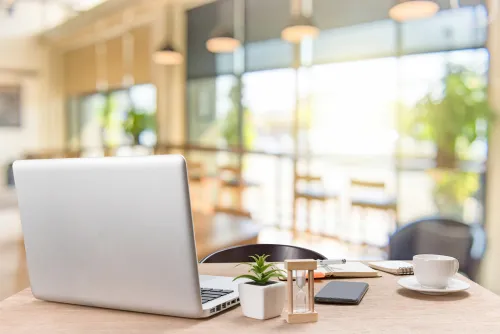 光のたくさん入るオフィスに置かれたPCやマグカップ