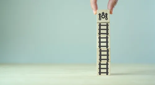 はしごと矢印が描かれた積み木をもつ手元