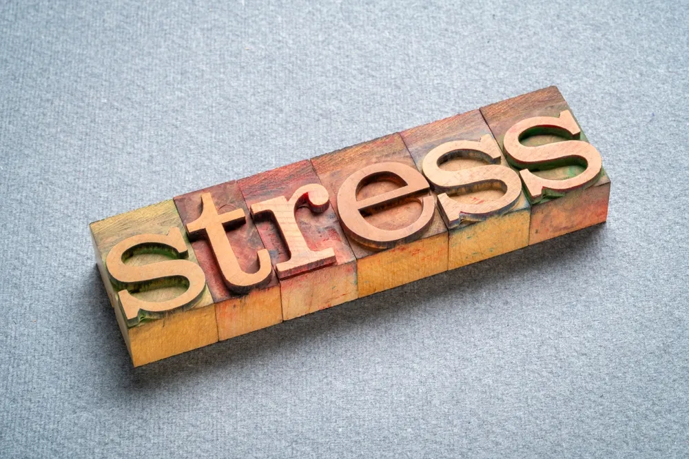 グレーの背景にstressと書かれた木の板