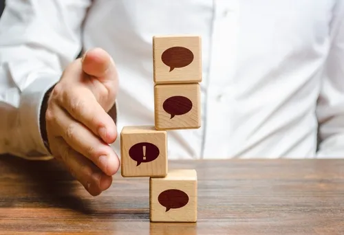 吹き出しが描かれた積み木が落ちないように支える手元