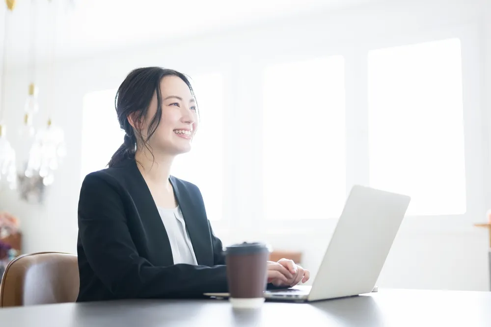 PCを開きながら笑顔の女性