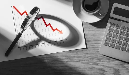 計算機とマグカップ、書類に立てかけられた虫眼鏡があるデスク