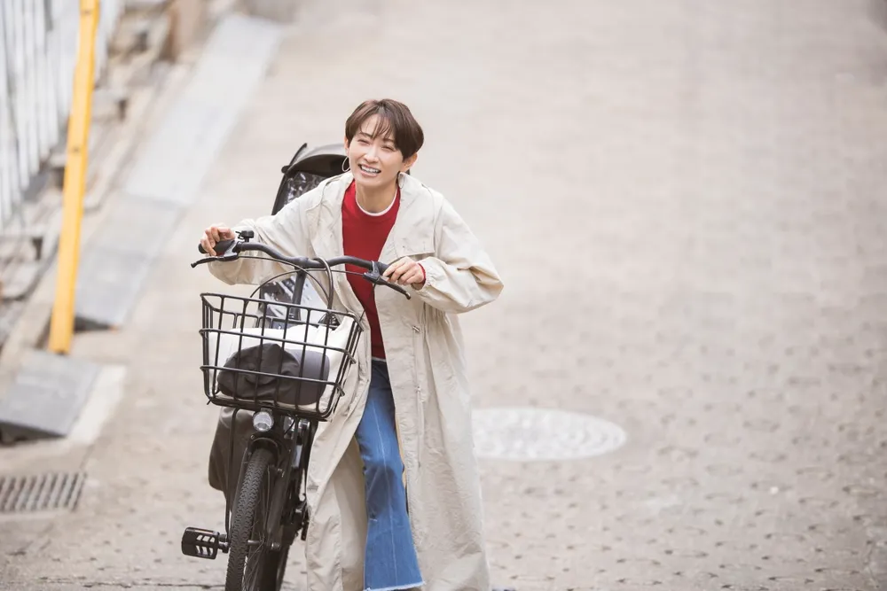 笑顔で自転車を押して歩く女性