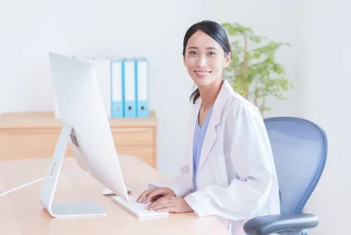 デスクトップパソコンを触る白衣を着た女性