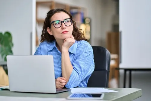 パソコンを開きあごに手をついて考える女性