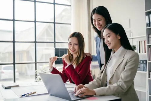 1台のパソコンを3人の女性で確認し微笑んでいる様子