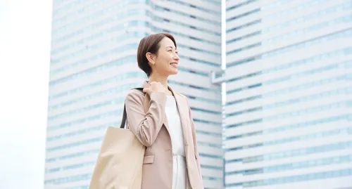 高層ビルを背景にショートヘアの女性が微笑む