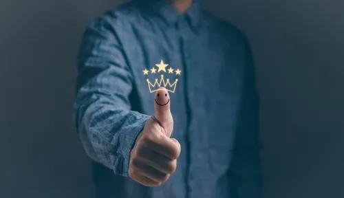 紺色のシャツを着た人の親指に描かれた顔と王冠のマーク