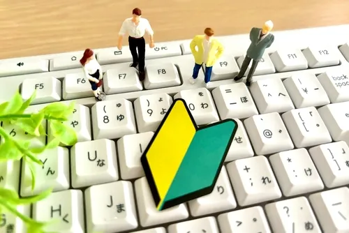 キーボードの上に置かれた人形と初心者マーク