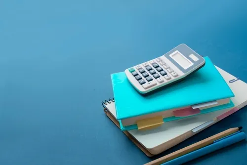 水色の背景に積み重ねられたノートや電卓