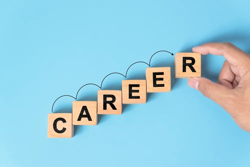 水色の背景にCAREERの文字が書かれたブロックを掴む手