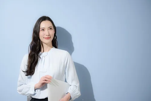 水色の背景にブラウスを着た女性が微笑む