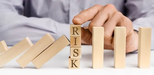 ドミノ倒しの中にRISKの文字の積み木を支える手元